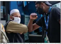  ?? (AP/Gemunu Amarasingh­e) ?? An Afghan man evacuated from Kabul elbow-bumps a support staff member Tuesday as he walks to a bus at Washington Dulles Internatio­nal Airport in Chantilly, Va.