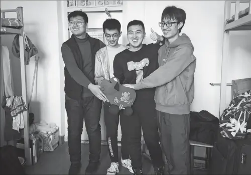  ?? PHOTO BY WANG YING / XINHUA ?? Cao Pengjun (second right), a junior at Northeaste­rn University in Shenyang, Liaoning province, celebrates Lunar New Year with three temporary roommates in the dormitory.