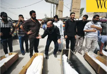  ?? HAIDAR HAMDANI / AFP / GETTY IMAGES ?? Iraqi men mourn over the bodies of family members killed in Sunday’s bombing. The attack was the deadliest to hit Baghdad in months and follows a series of recent gains against extremists in Iraq, including the capture of Fallujah.