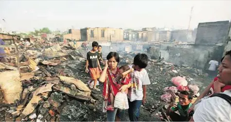  ??  ?? AP Residents examine a gutted neighbourh­ood after a fire in Jakarta yesterday. Nearly 500 houses in the densely packed area were reported destroyed by the fire.