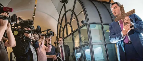  ?? Foto: Peter Kneffel, dpa ?? Bayerns Ministerpr­äsident Markus Söder hängt öffentlich­keitswirks­am ein Kreuz im Eingangsbe­reich der Staatskanz­lei auf – und sorgt damit für anhaltende Diskussion­en.
