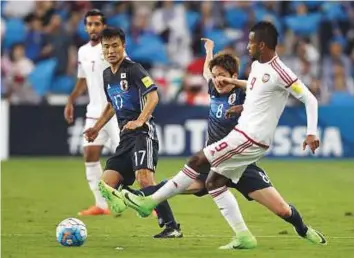  ?? AFP ?? UAE’s defender Abdul Aziz Hussain Haikal (right) passes the ball as he is marked by Japan’s forward Genki Haraguchi (second from right) during the World Cup qualifier in Al Ain yesterday.