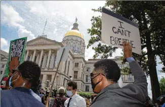  ?? STEVE SCHAEFER / FOR THE AJC ?? Marchers hold up signs at the state Capitol during a march Thursday. Many leaders are looking for ways to heal the racial divide.