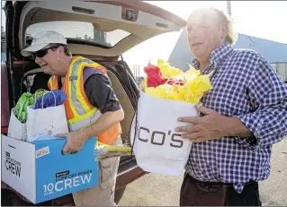  ?? PHOTOS BY ALLEN EYESTONE / THE PALM BEACH POST ?? Aaron Hoffman (left) and the Rev. Clayton Waddell deliver gift bags to the crew of the Duke of Topsail at the Port of Palm Beach recently. The bags are filled with hand-knitted hats, scarves, toiletries and other items prepared by the nonprofit Port of Palm Beach Seafarers’ Center.