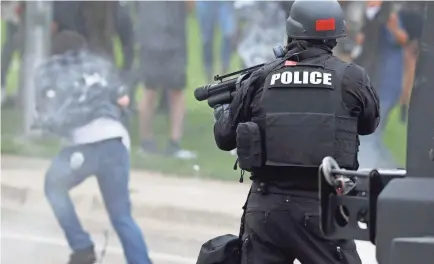  ?? DAVID ZALUBOWSKI/AP ?? A Denver police officer fires a projectile at a retreating protester after a demonstrat­ion at the State Capitol on May 30. Civil rights watchdogs have assailed the use of what law enforcemen­t calls “kinetic impact projectile­s.”