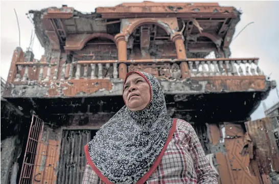  ??  ?? TIME TO START AGAIN: Lenang Cali stands in front of the wreckage of her home and bakery shop during a brief return to Marawi.