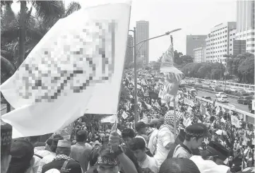  ??  ?? Indonesian Muslims, carrying flags and banners, march toward Parliament to mark the 52nd anniversar­y of the murder of six army generals and a young lieutenant by rebel armed forces personnel during an abortive coup against then president Sukarno in...