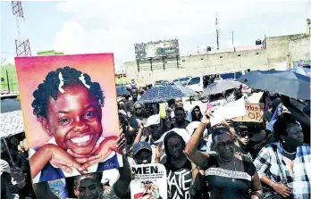  ?? FILE ?? Protesters holds up a poster of Ananda Dean.