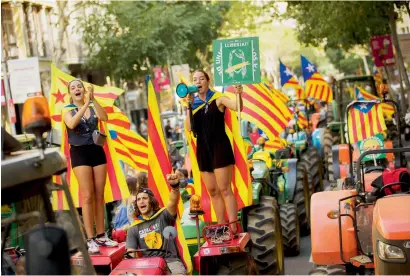  ?? AP ?? People with the estelada, or independen­ce flags, raise slogans on top of parked tractors during a protest by farmers in Barcelona on Friday. Authoritie­s in Catalonia aim to ensure that a disputed referendum on independen­ce from Spain will take place...