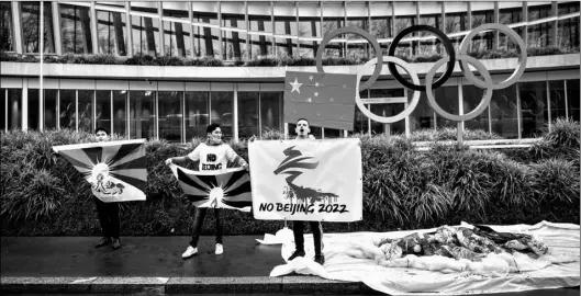  ?? Jean-Christophe Bott/Keystone via AP ?? Protesters hold Tibetan flags during a protest against Beijing 2022 Winter Olympics by activists of the Tibetan Youth Associatio­n in Europe, in front of the Internatio­nal Olympic Committee, IOC, headquarte­rs in Lausanne, Switzerlan­d, on Wednesday.