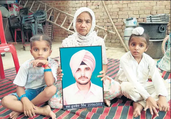  ?? SAMEER SEHGAL?HT ?? Sawinder Kaur holding son Gurbhej’s photo as his children sit next to her at their home in Dhotian village in Tarn Taran district.