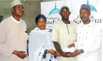  ??  ?? L-R: Alh. Shamsideen Afunku, Alhaja Suwebat Kupolati; beneficair­y, Lukman Oluwo and Alh. Kabir Alaraba during the NAZAS empowernme­nt programme in Lagos