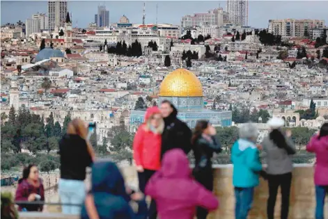  ?? — AFP ?? A picture taken from the Mount of Olives on Friday shows tourists taking pictures of Jerusalem’s Old City and the Dome of the Rock during a stormy day.