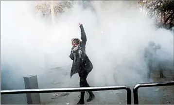  ?? GETTY-AFP ?? An Iranian woman raises her fist amid the smoke of tear gas at the University of Tehran during protests on Saturday.