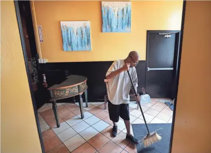  ??  ?? James Jackson tidies up the waiting area at a new Caribbean restaurant in Downtown Memphis. Jackson’s brother-in-law Arturo Azcarate is opening Curry N Jerk this week . PHOTOS BY JIM WEBER/THE COMMERCIAL APPEAL