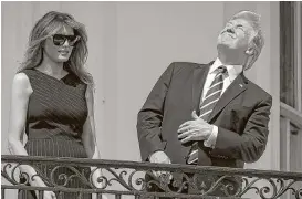  ?? Al Drago / New York Times ?? President Donald Trump and first lady Melania Trump view the solar eclipse from the Truman balcony of the White House. He later put on eclipse glasses.