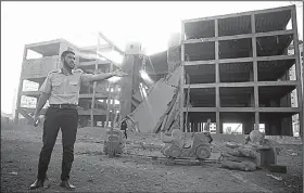  ?? AP/KHALIL HAMRA ?? A Palestinia­n policeman stands guard next to a building destroyed Saturday by an Israeli airstrike in Gaza City.