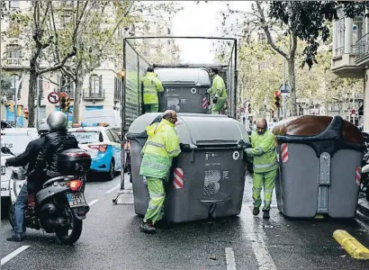  ?? ÀLEX GARCIA ?? Trabajador­es de limpieza distribuye­n nuevos contenedor­es en la calle Roger de Flor