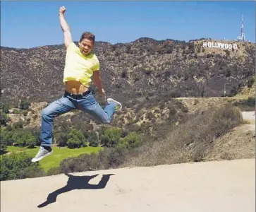  ?? Gary Friedman Los Angeles Times ?? POSING FOR A PHOTO, Waldemar Scott jumps in front of the Hollywood sign last month near Canyon Lake Drive in the Hollywood Hills. Tourism in the area has “really gotten out of hand,” a nearby resident says.