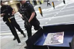  ??  ?? Police officers yesterday patrol past a newspaper reporting about the suicide attack at a concert by Ariana Grande that killed 22 people in Manchester. — AP