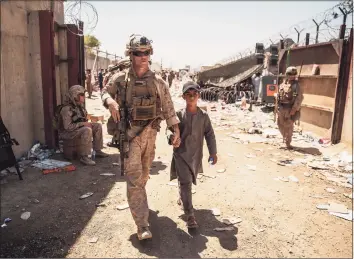  ?? Staff Sgt. Victor Mancilla / Associated Press ?? A U.S. Marine escorts a child during ongoing evacuation­s at Hamid Karzai Internatio­nal Airport, Kabul, Afghanista­n, on Tuesday.