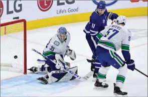  ??  ?? The Canadian Press
Toronto Maple Leafs left-wing Zach Hyman and Canucks defenceman Tyler Myers watch as Leafs centre Jason Spezza (not shown) score past Thatcher Demko in Toronto on Thursday.