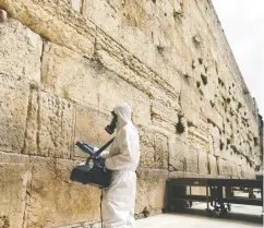  ?? Ammar Awa d / Reuters ?? A labourer sanitizes the stones of the Western Wall ahead of the Jewish holiday of Passover, in Jerusalem.