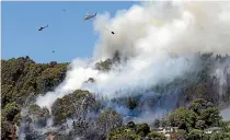  ?? STUFF ?? Helicopter­s with monsoon buckets fight a fire in trees in Nelson yesterday.