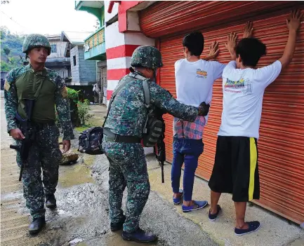  ?? (Romeo Ranoco/Reuters) ?? A GOVERNMENT SOLDIER frisks a resident who evacuated his home in Sarimanok village, Marawi City, Philippine­s last week during an ongoing assault of government troops on insurgents from the Maute group, who have taken over large parts of the city.