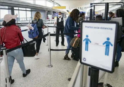  ?? John Minchillo/Associated Press ?? Transporta­tion Security Administra­tion personnel and travelers observe COVID-19 transmissi­on prevention protocols at John F. Kennedy Internatio­nal Airport in New York.