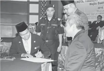  ??  ?? Sufian signing his letter of appointmen­t before Awang Tengah.