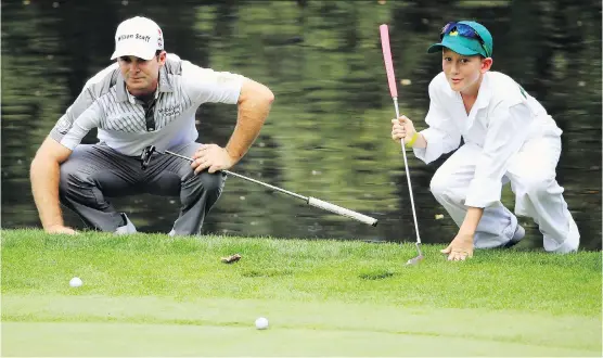  ?? JAMIE SQUIRE/ GETTY IMAGES ?? Kevin Streelman, left, of the United States lines up a putt with the help of his caddy, Spruce Grove's Ethan Couch, during the Par 3 Contest prior to the start of the 2015 Masters Tournament at Augusta National Golf Club.