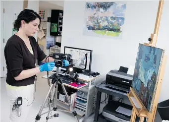  ?? AP PHOTO/Evan Vucci ?? Patricia Favero, conservato­r at The Phillips Collection, sets up an infrared camera to view an image of a manfound underneath one of Picasso’s first masterpiec­es, The Blue Room, in Washington.