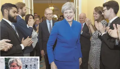  ?? AP PHOTOS ?? THE DAY AFTER: Britain’s Prime Minister Theresa May, above, is applauded by staff at 10 Downing St., after receiving permission from Queen Elizabeth II to form a new government. Left, protesters call for her to resign after her party lost its majority.