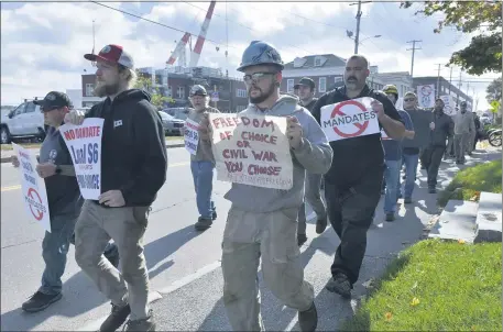  ?? JOSH REYNOLDS — THE ASSOCIATED PRESS ?? Justin Paetow, center, a tin shop worker at Bath Iron Works, takes part in a demonstrat­ion against COVID-19 vaccine mandates outside a shipyard Friday in Bath, Maine.