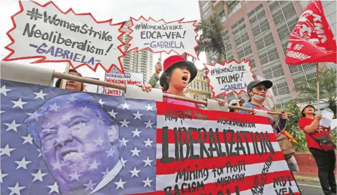  ??  ?? MANILA: Filipino women display a mock American flag with the portrait of US President Donald Trump on it as they march for a rally at the US Embassy to mark Internatio­nal Women’s Day. — AP