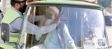  ?? Associated Press ?? ↑
A police officer explains how to wear a mask for an auto rickshaw driver in Peshawar on Monday.