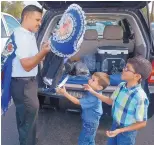  ??  ?? Tim Lucero hands his cupil — the headdress worn by male Matachines dancers — to his sons Aiden, 4, and Brandon, 6, to carry into Our Lady of Sorrows Catholic Church on Thursday.