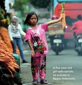  ??  ?? A five-year- old girl sells carrots on a street in Bogor, Indonesia.