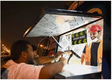  ?? - AFP ?? Low times: Bader working hard in his food truck at a main street in Riyadh to cook and serve customers - something previously considered worthy only for lowly expat workers.