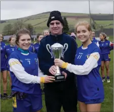  ??  ?? Coláiste Bhríde joint captains Aisling Winterboth­am and Siofra Byrne accept the cup from Jim Murphy.