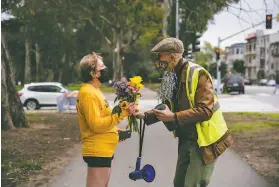  ??  ?? Pedestrian hitandrun survivor John Lowell hands Julie Nicholson flowers at the end of her half marathon marking the anniversar­y of her own accident.