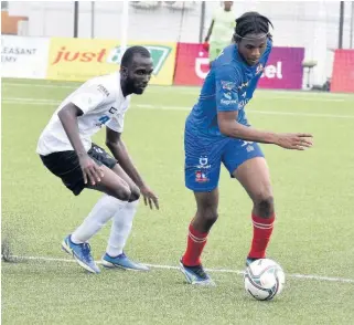  ?? KENYON HEMANS ?? Dunbeholde­n’s Rushawn Taylor (right) turns away from Cavalier’s Nickache Murray during a Jamaica Premier League game at the UWI-JFF Captain Horace Burrell Centre of Excellence on Monday, March 7, 2022.