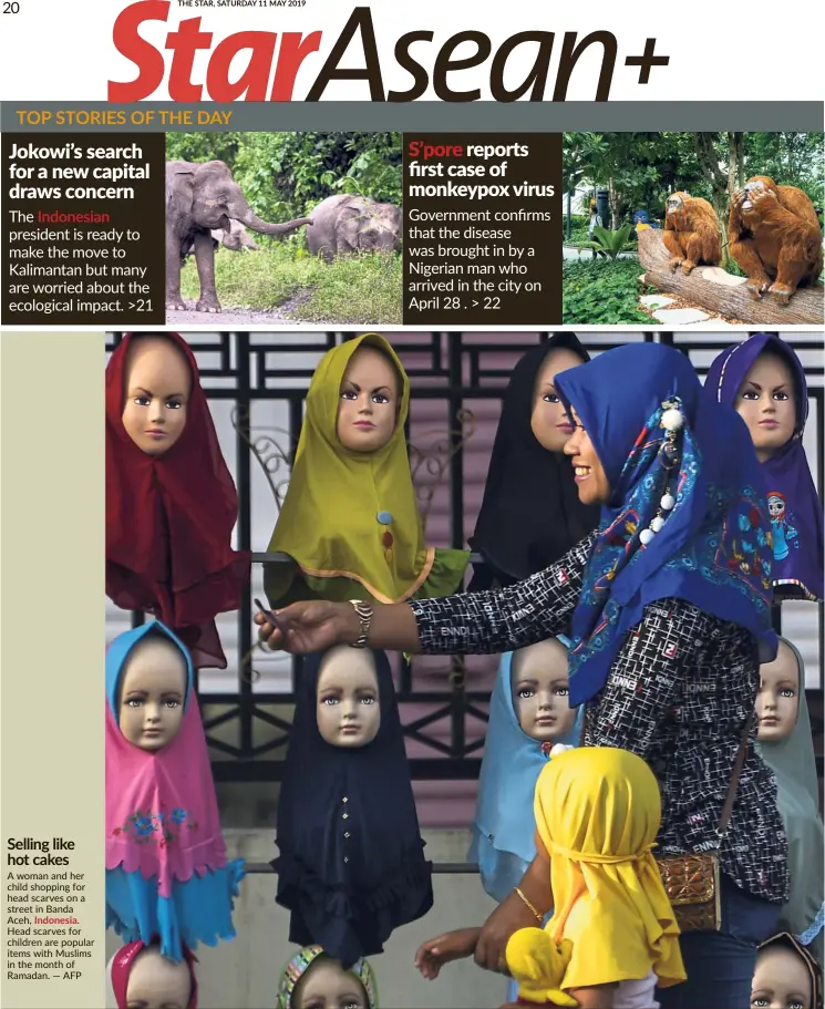  ?? — AFP ?? Selling like hot cakes A woman and her child shopping for head scarves on a street in Banda Aceh, Indonesia.
Head scarves for children are popular items with Muslims in the month of Ramadan.