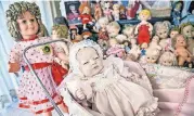  ??  ?? A 50th Edition Shirley Temple Doll stands near a baby doll in a buggy surrounded by other pieces of Imogene McDowell’s collection of more than 500 dolls at her Mustang home.