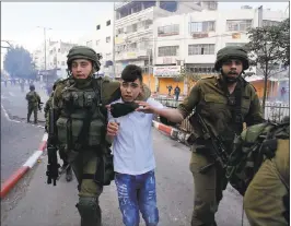  ?? NASSER SHIYOUKHI — THE ASSOCIATED PRESS ?? Israeli soldiers detain a Palestinia­n boy in the West Bank city of Hebron at a protest against President Trump’s decision to recognize Jerusalem as the capital of Israel.