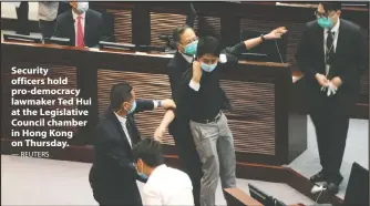  ?? — REUTERS ?? Security officers hold pro-democracy lawmaker Ted Hui at the Legislativ­e Council chamber in Hong Kong on Thursday.