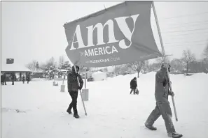  ?? Associated Press ?? ■ Volunteers Tim Schumann, left, and Chase Cushman move an “Amy for America” sign into place Sunday prior to Democratic Sen. Amy Klobuchar’s announceme­nt of her decision in the race for president at a rally in Minneapoli­s.