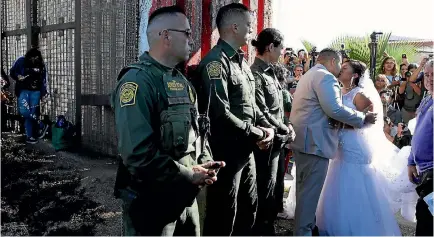 ?? PHOTOS: REUTERS ?? American resident Brian Houston marries Evelia Reyes as US Border Patrol agents open a single gate in the border wall to allow selected families to visit along the USMexico border at Border Field State Park in San Diego, California.