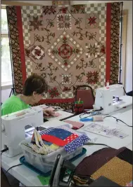  ?? ?? Ola Bramlett works on her quilt at QuiltMania. In the background hangs the group’s donation quilt, which is being raffled off to raise money so the group can provide free quilts to charity. Tickets are sold at the Third Thursday Street Festival in downtown Benton through September.